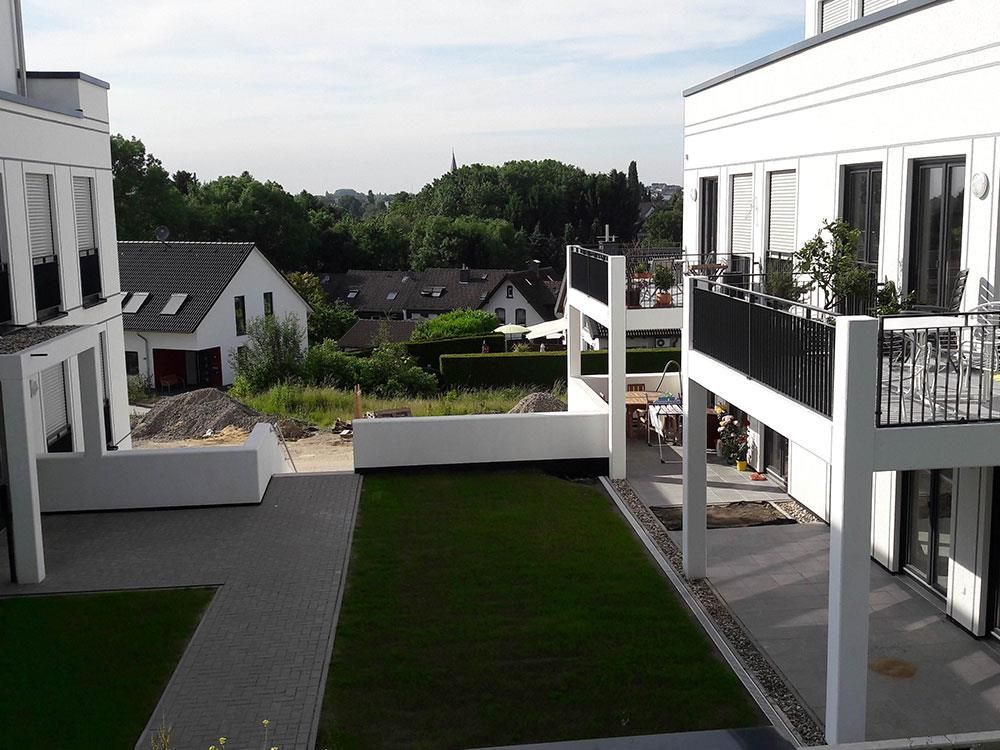 Ein weißes Gebäude mit einem Balkon und einer Wiese davor