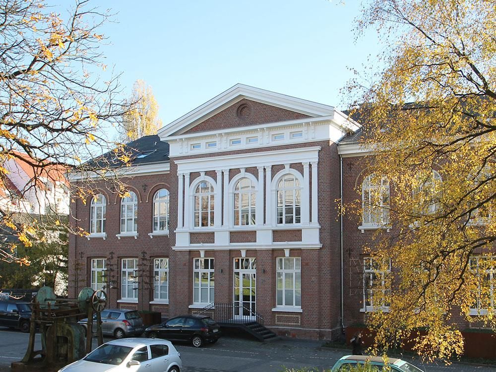 Ein weißes Auto steht vor einem großen Backsteingebäude