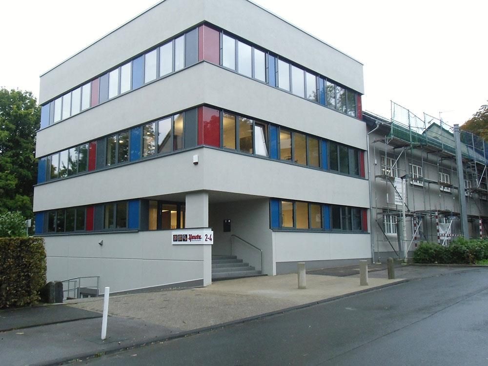 Ein großes weißes Gebäude mit roten, blauen und schwarzen Fenstern