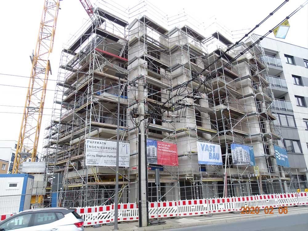 Ein im Bau befindliches Gebäude mit Gerüst und einem Kran im Hintergrund.