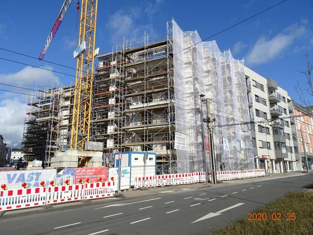 Ein großes Gebäude im Bau mit Gerüsten und einem Kran im Hintergrund