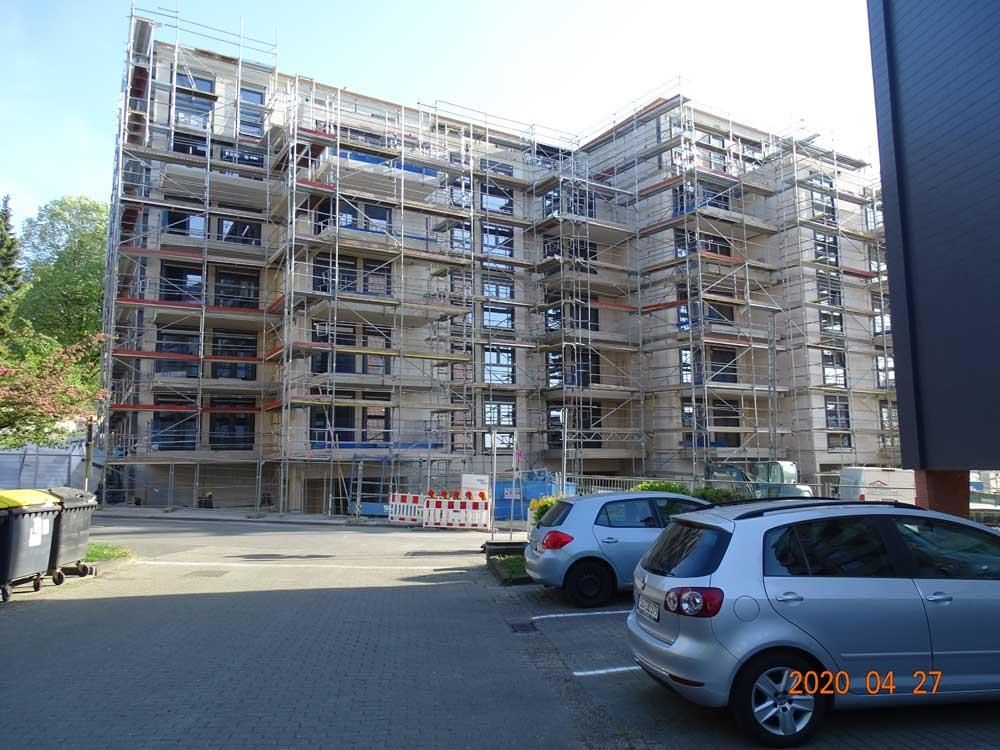 Ein silbernes Auto steht vor einem im Bau befindlichen Gebäude