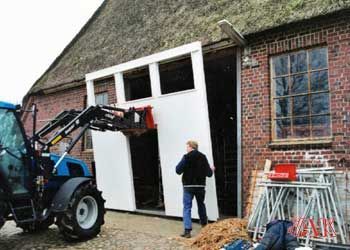 Ein Mann steht vor einem Traktor vor einem Backsteingebäude.