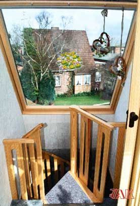 Eine Holztreppe mit Blick auf ein Haus durch ein Fenster.