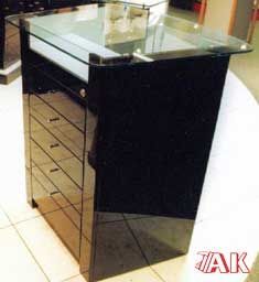 Eine schwarze Kommode mit Glasplatte steht auf einem gefliesten Boden.