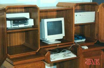 Ein Computer steht neben einem Drucker auf einem Holzschreibtisch.