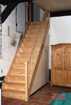 Eine Holztreppe in einem Zimmer mit einem Kleiderschrank und einem Teppich.