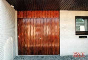 Ein weißes Backsteingebäude mit einem hölzernen Garagentor und einem Fenster.