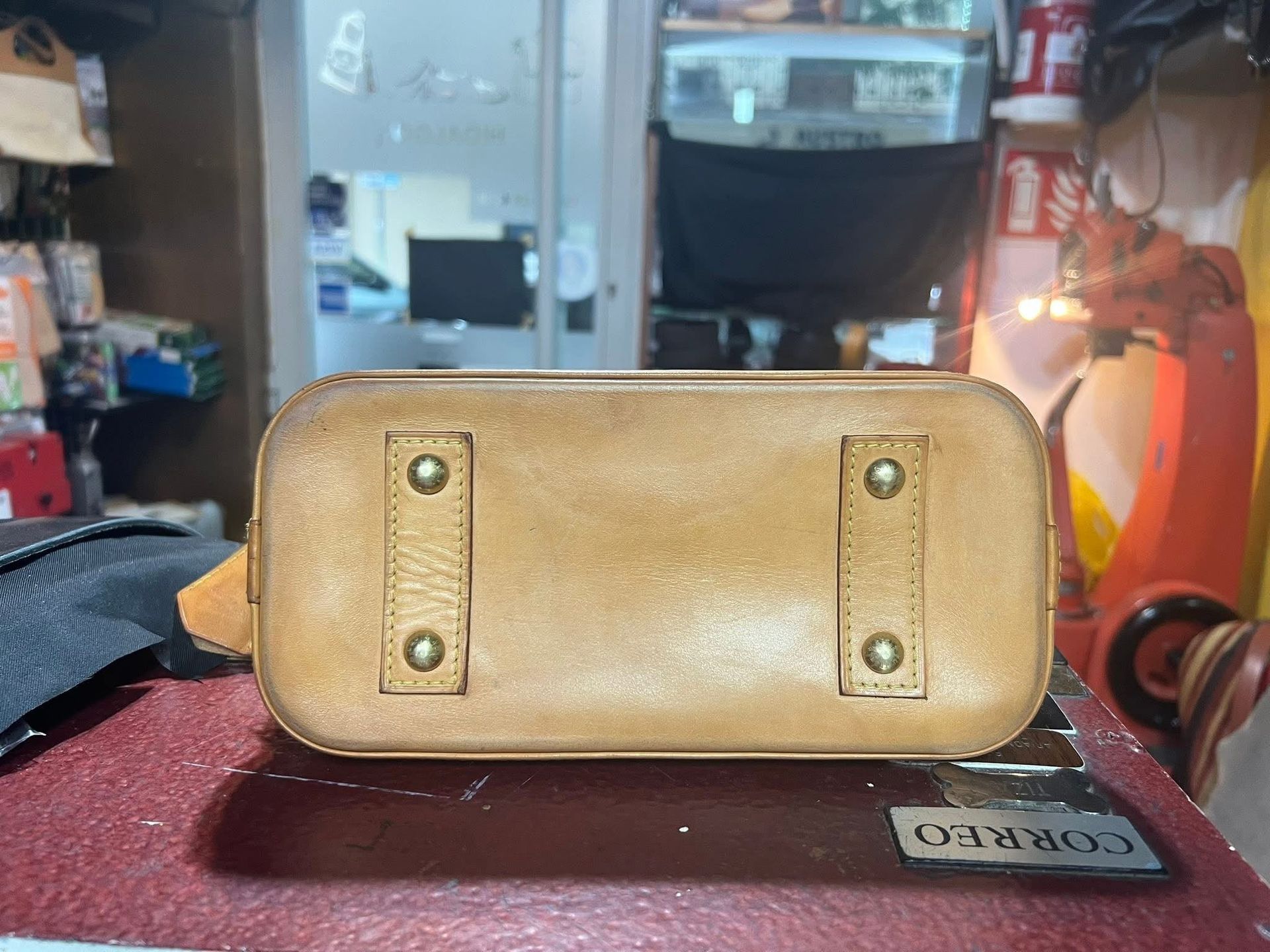 Bolso o maletín de cuero marrón claro sobre una superficie roja en una habitación interior desordenada