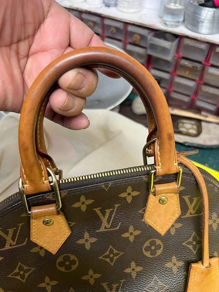 Primer plano de un bolso marrón de Louis Vuitton con asas de cuero color canela, sostenido con una mano