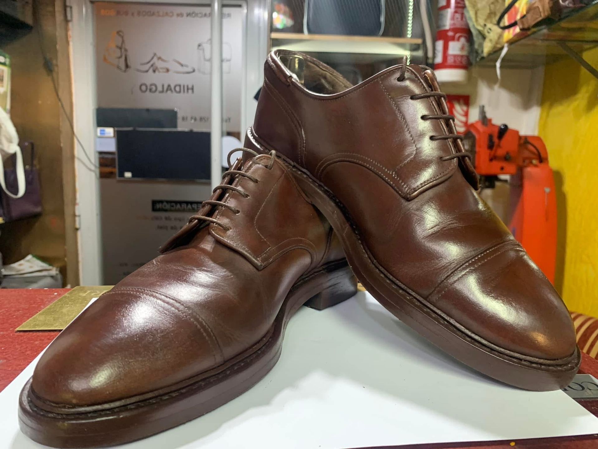 Botas de vestir de cuero marrón, colocadas una al lado de la otra sobre una mesa en un taller