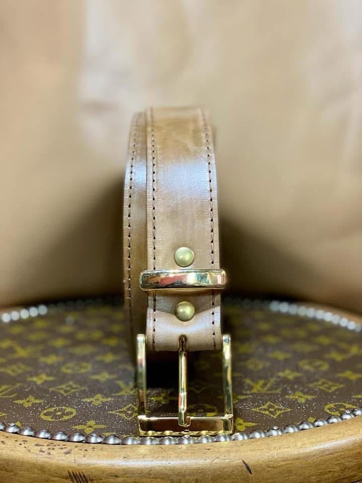 Hebilla de cinturón de cuero marrón sobre una cesta tejida con motivos decorativos