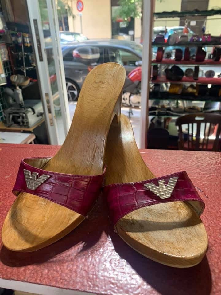 Sandalias de mujer rosas y doradas expuestas en el mostrador de una tienda, con zapatos visibles al fondo