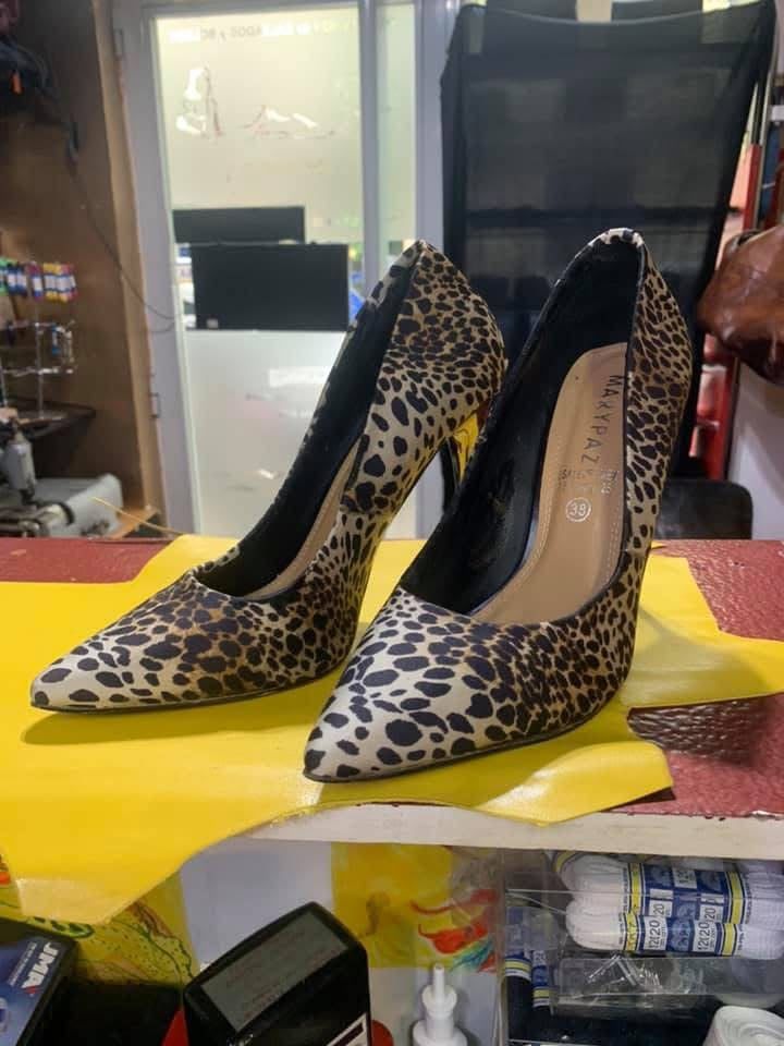 Zapatos de tacón alto con estampado de leopardo y punta afilada sobre una caja amarilla en el escaparate de una tienda