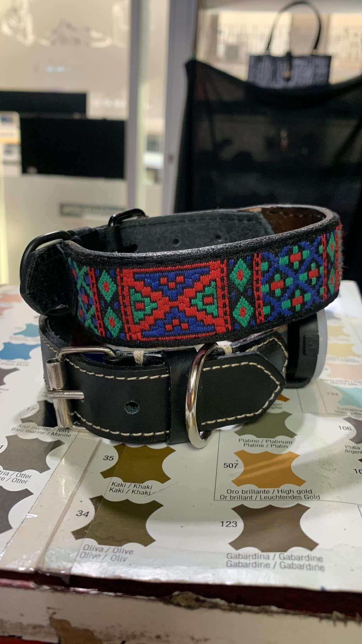 Collar colorido de tela tejida para perro con hebilla de cuero negro, sobre una mesa estampada en el interior