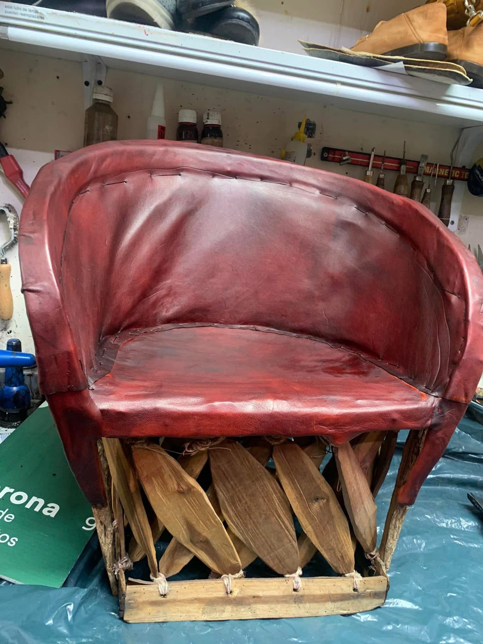 Silla de cuero rojo con base de madera trenzada en un taller o estudio