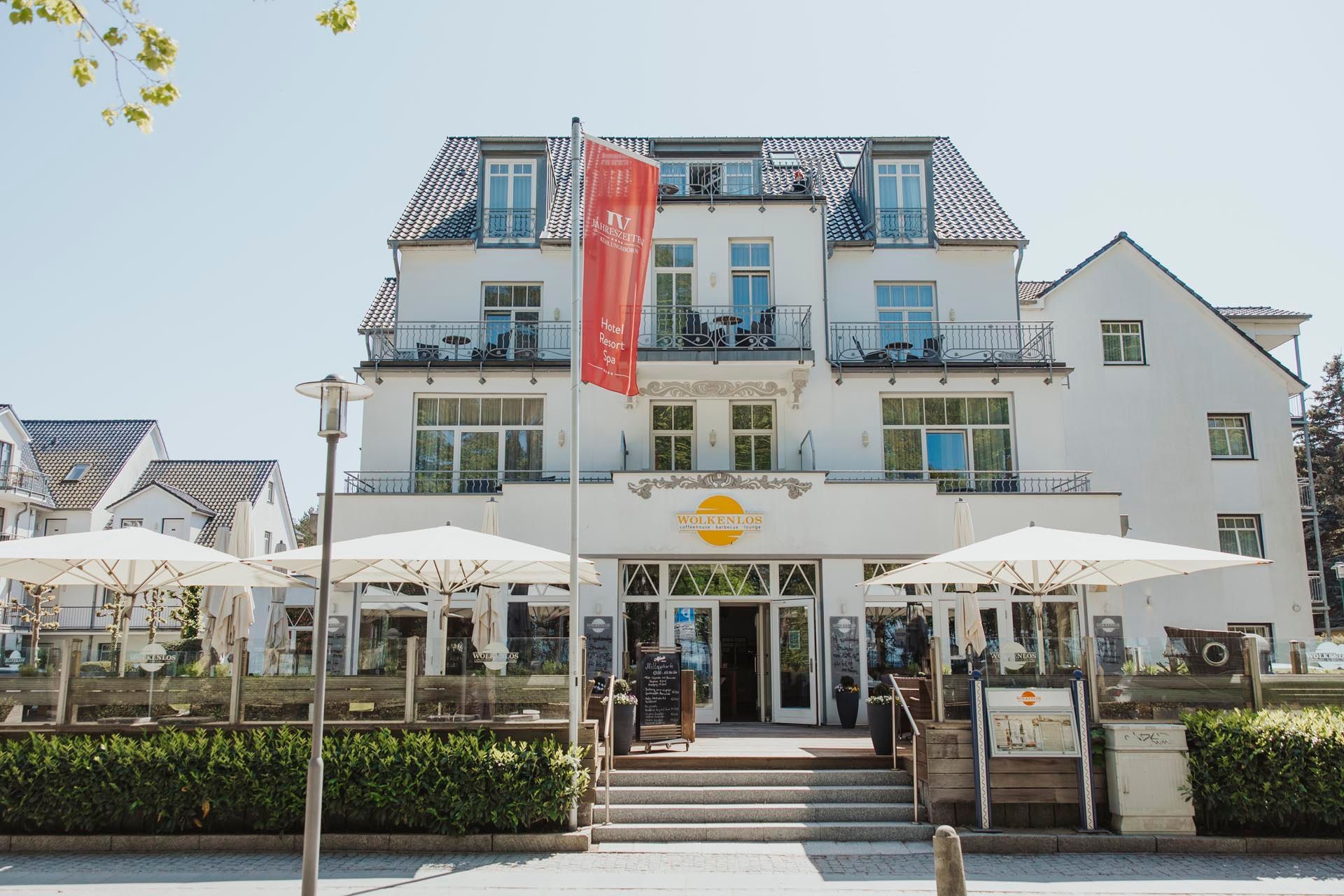 Weißes Gebäude mit Restaurantterrasse. Rote Flagge. Strahlend blauer Himmel.