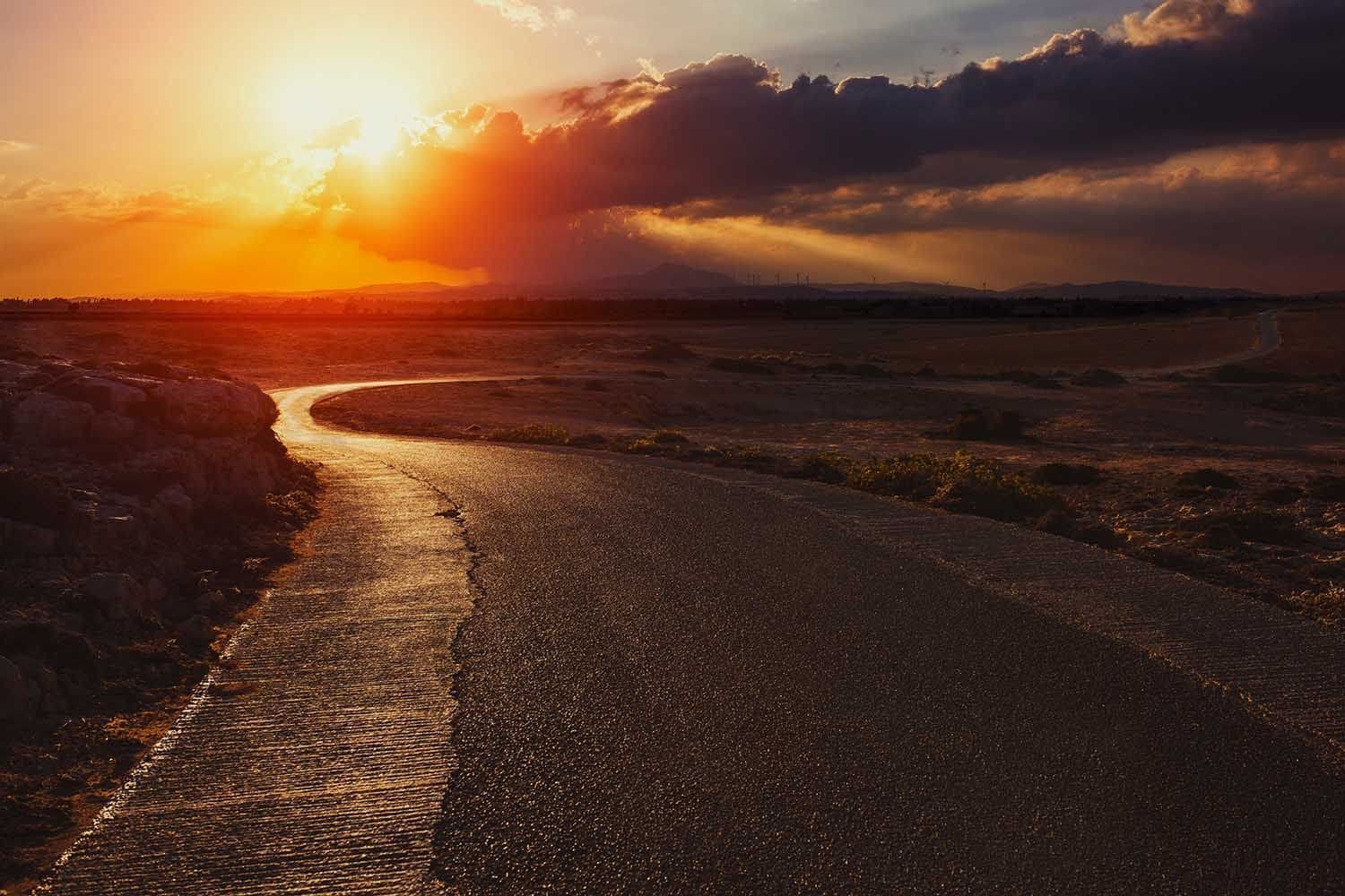 Sunset over a winding reflective river across a dark coastal plain