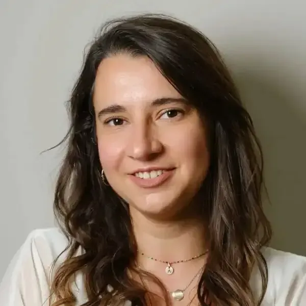 Mujer de cabello castaño sonríe a la cámara