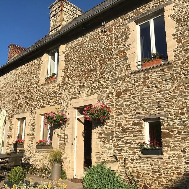 La façade d'une maison en pierre avec une porte d'entrée centrale.