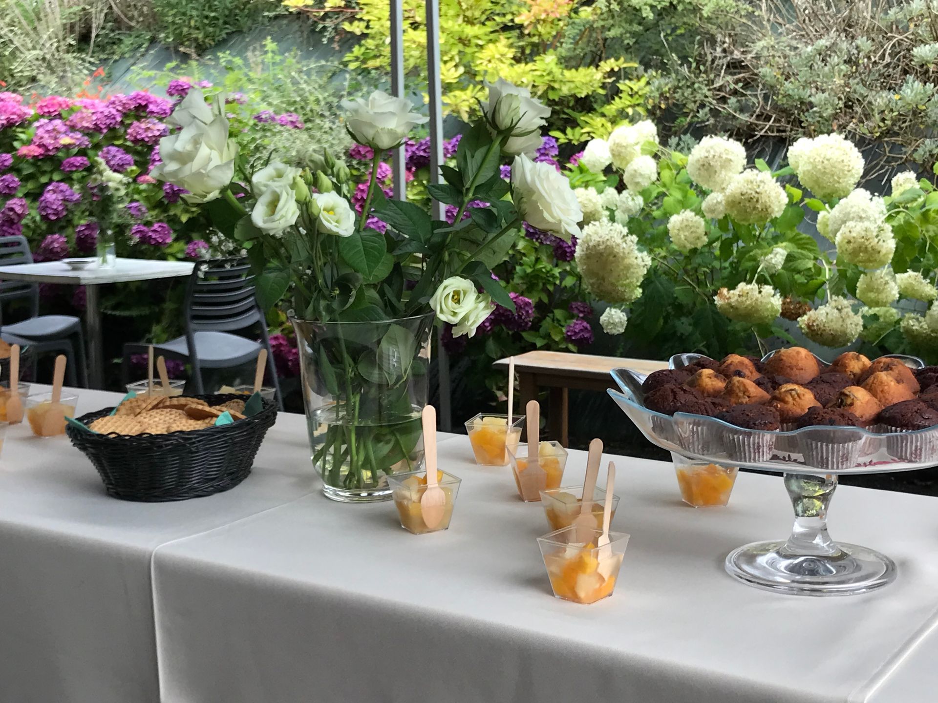 Buffet avec fleurs, desserts et boissons lors d'un événement en plein air dans un jardin