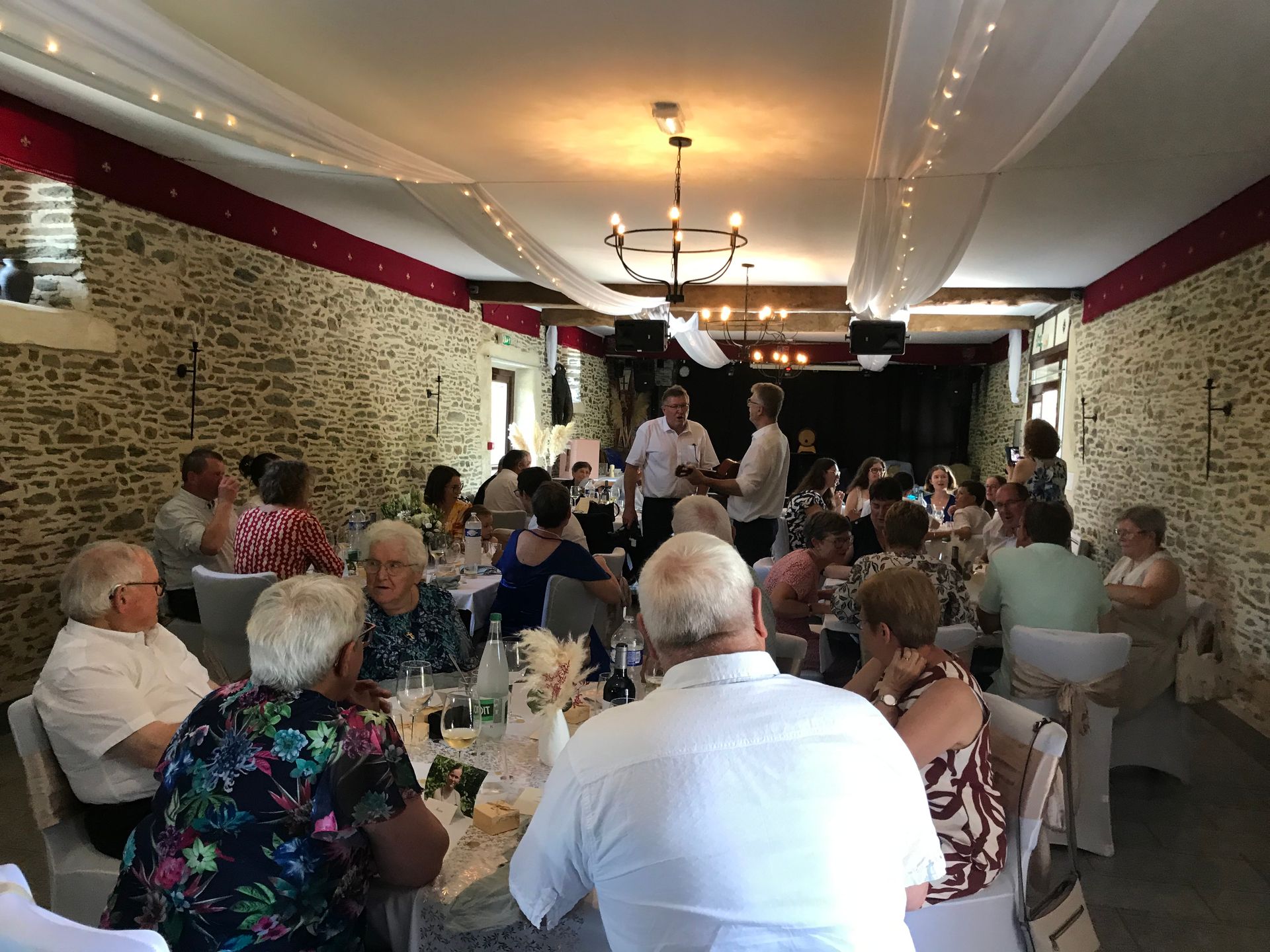 Des personnes assises à de longues tables dans une salle à manger décorée