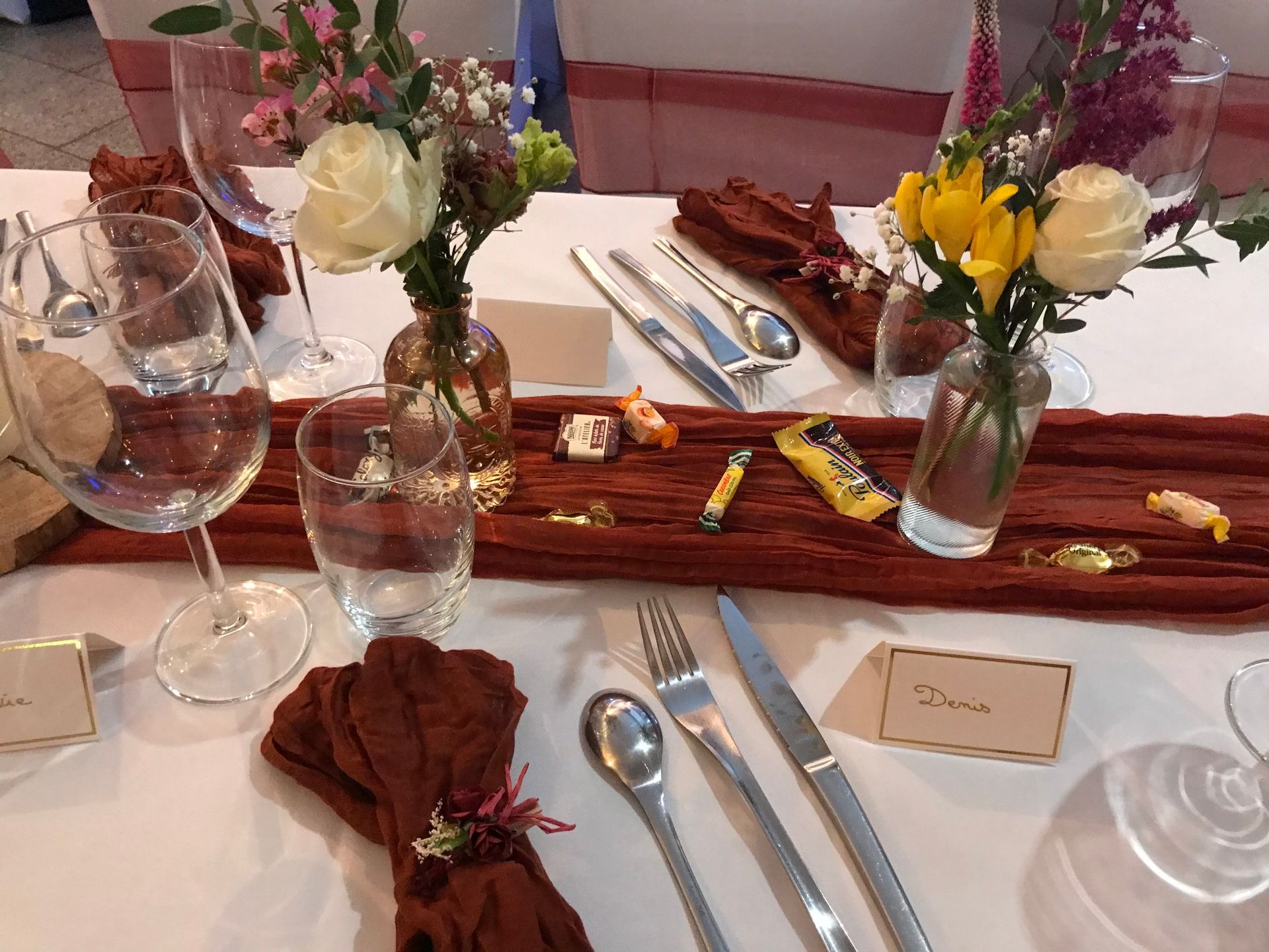 Un buffet sur une nappe orange, présentant un présentoir à trois étages de petits pains et d'amuse-gueules assortis, en extérieur.