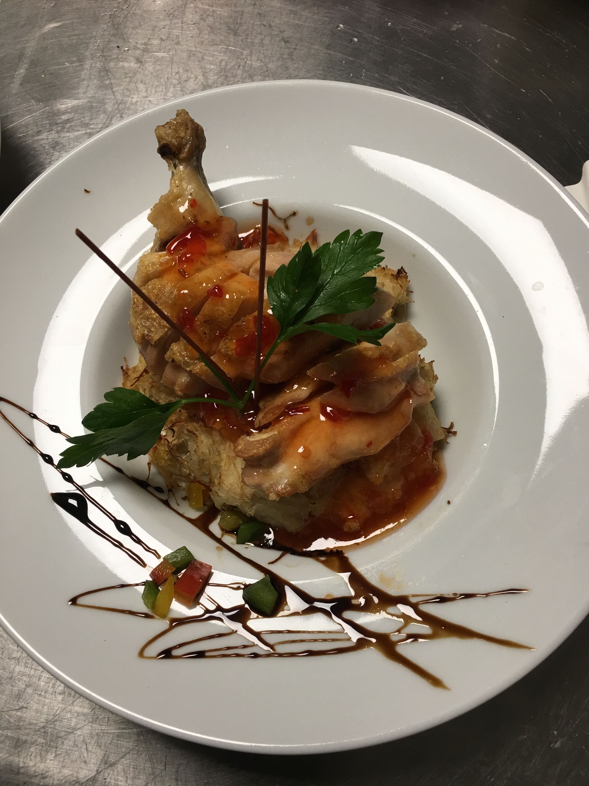 Amuse-bouche gastronomique présenté sur une assiette blanche, nappé de sauce et garni de persil.