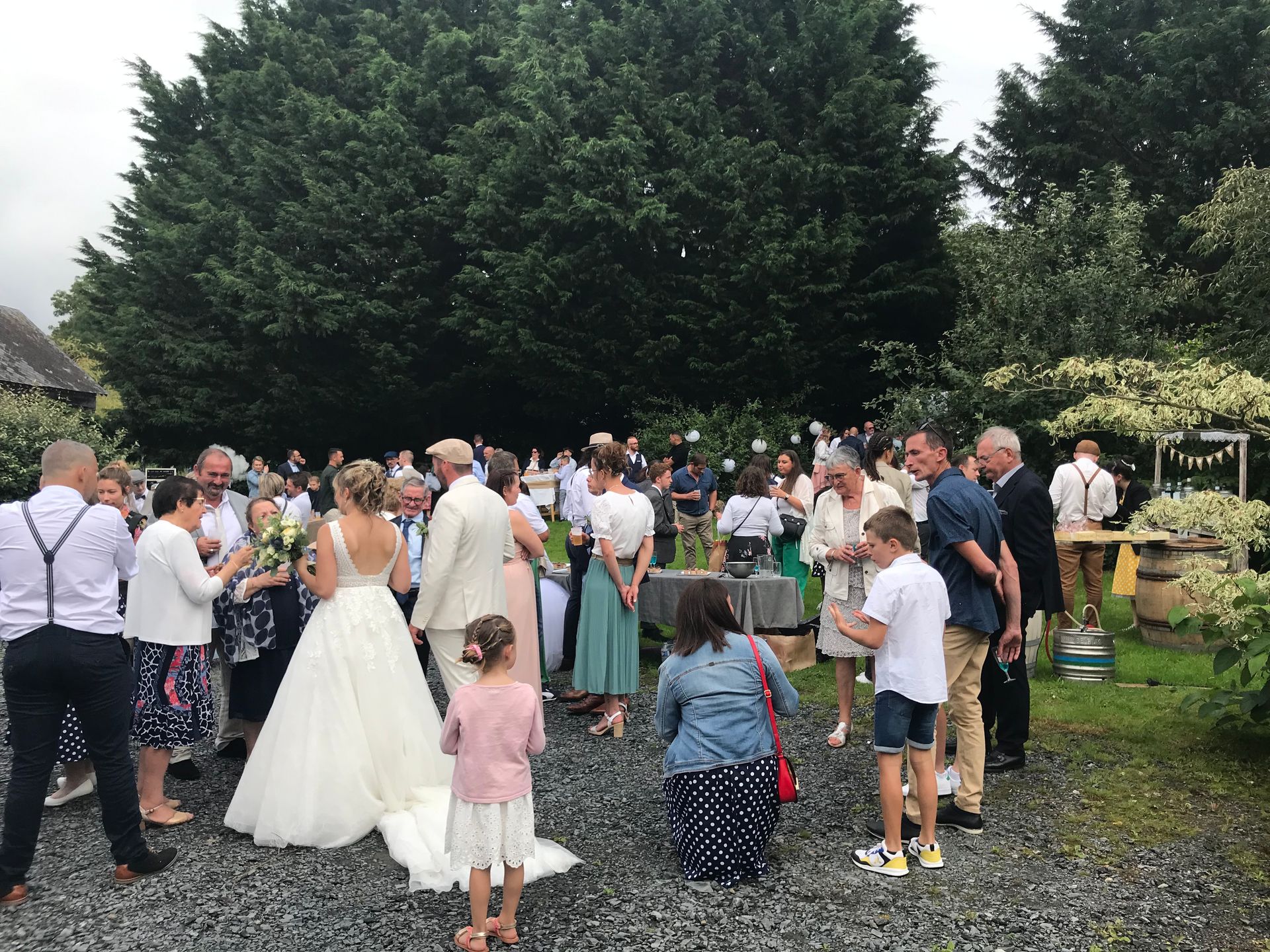 Mariage en plein air avec les invités autour de la mariée en robe blanche dans un jardin
