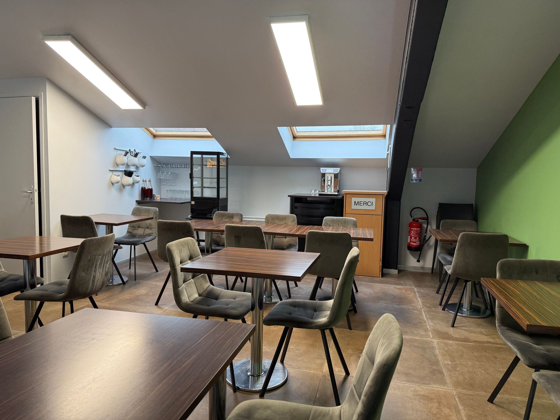 L'intérieur vide d'un café, avec des tables et des chaises, de la lumière naturelle provenant de puits de lumière.