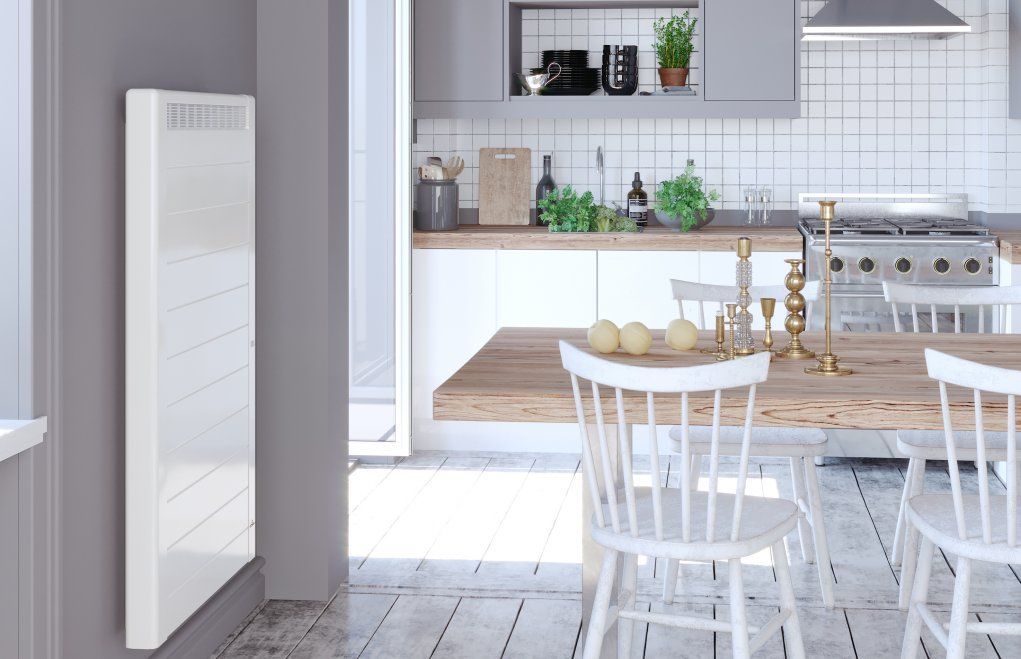 Un technicien installe une plaque de cuisson à induction noire sur un plan de travail en béton dans une cuisine moderne.