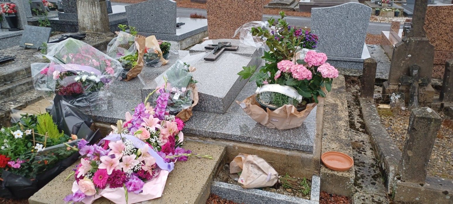Tombe au milieu d'un cimetière avec de nombreuses décorations florales