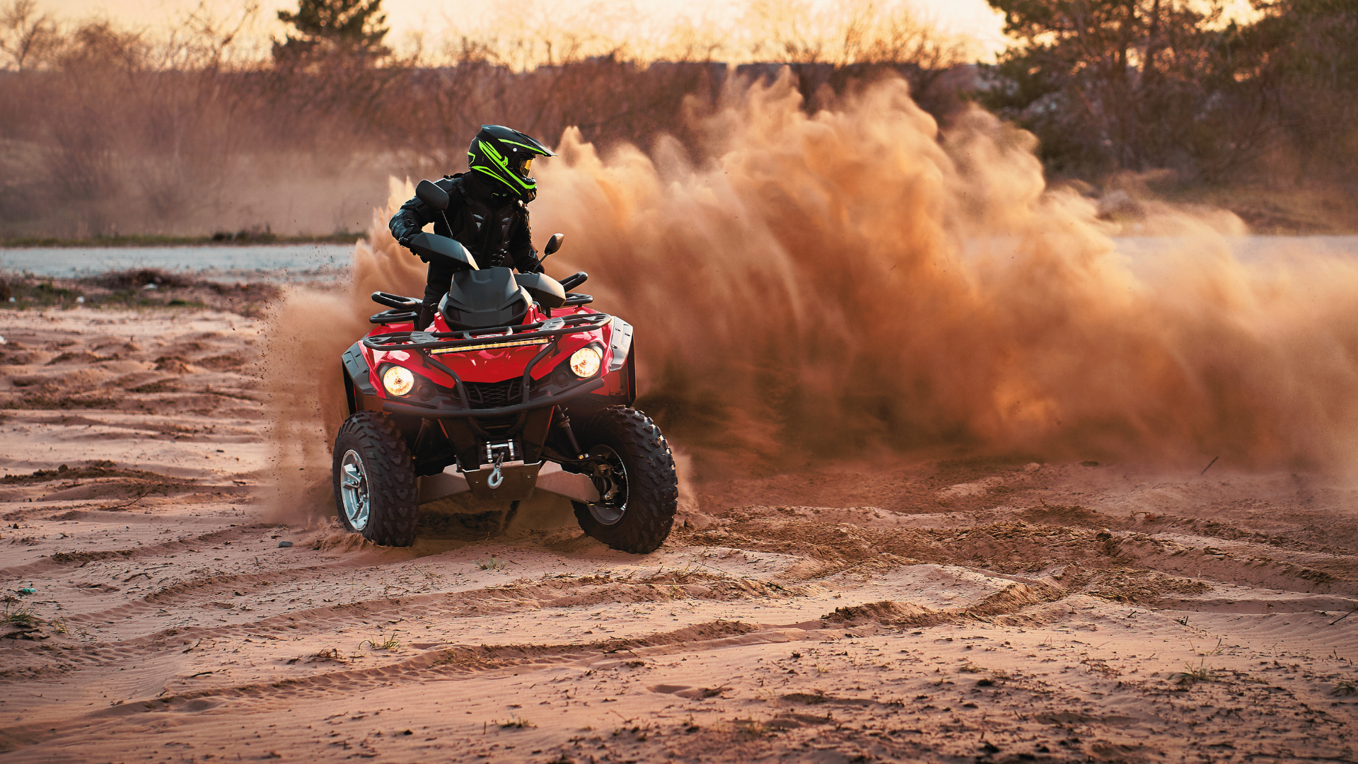 Person riding ATV throughout the dirt and kicking up dust behind them