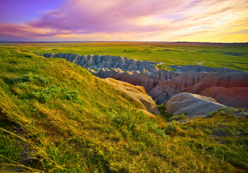 Green, grassy field with boulder rocks with a beautiful sunset in the background in SD