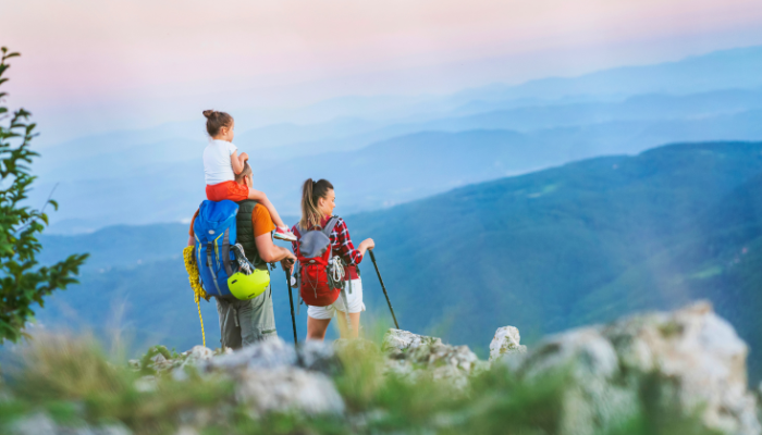 Family hiking outdoors with beautiful hills and color sky in the background