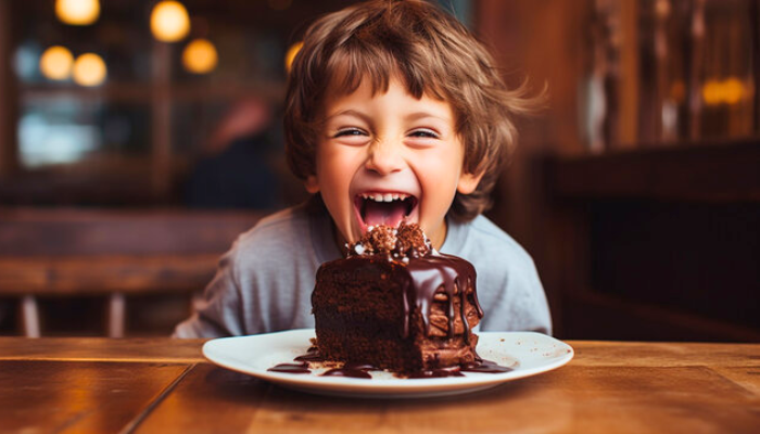 Small child excited about his large chocolate cake sitting on table