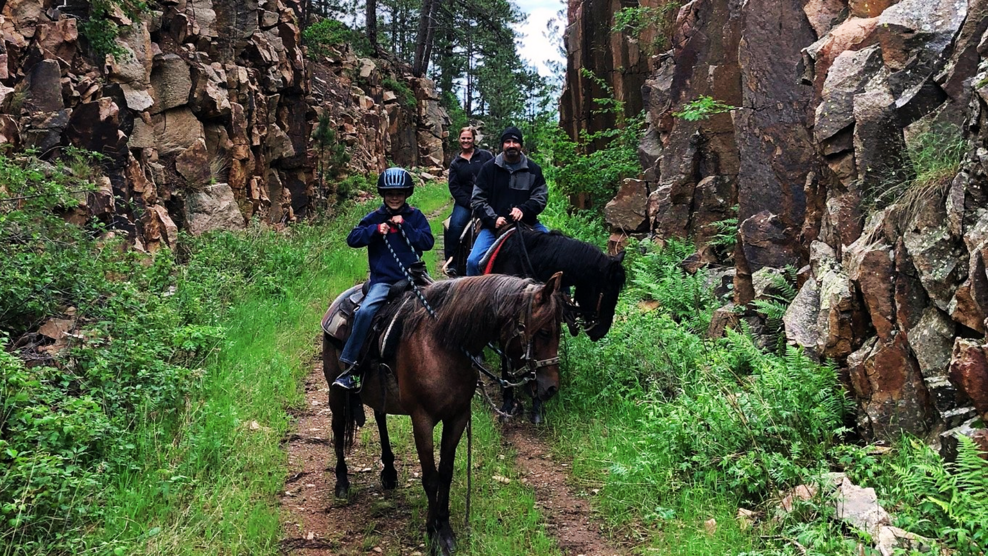 Family horseback riding through wilderness trails