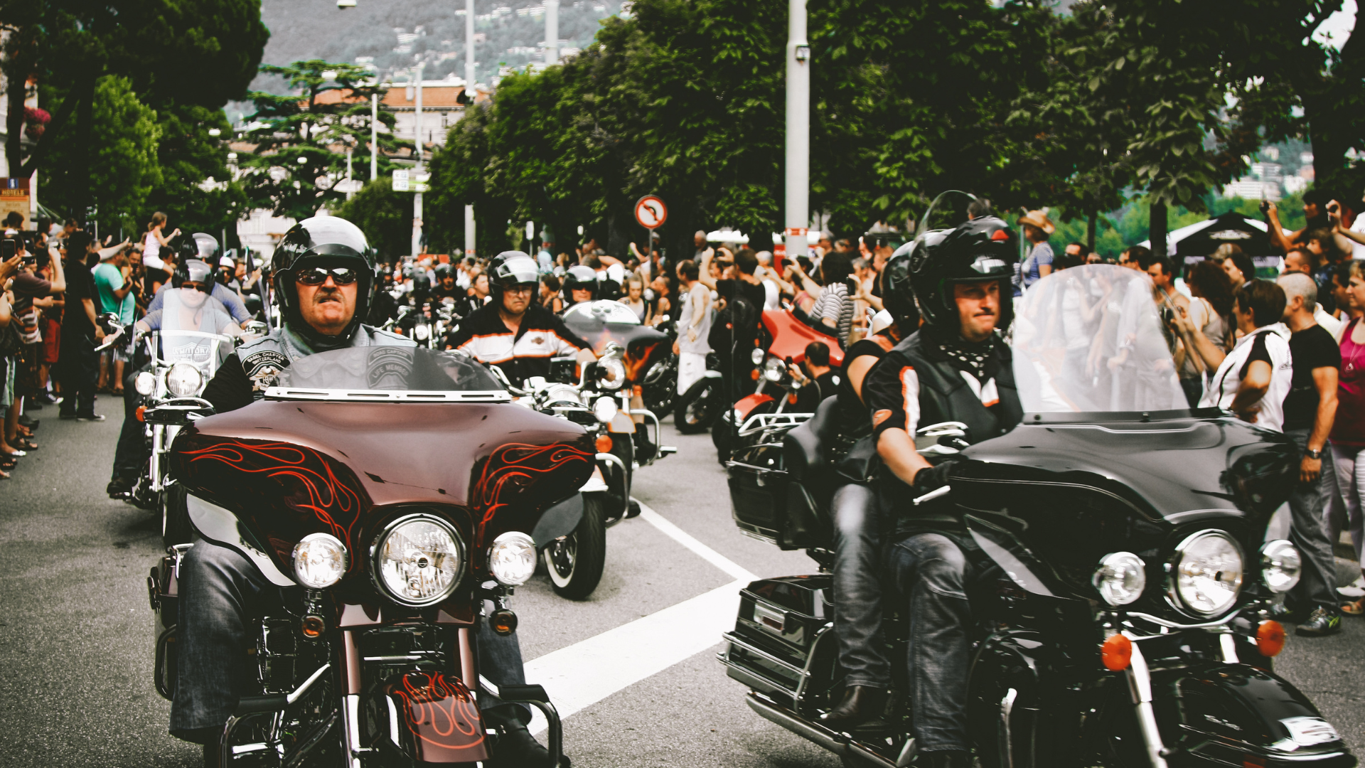Group of motorcyclists in a large group together, riding down the street