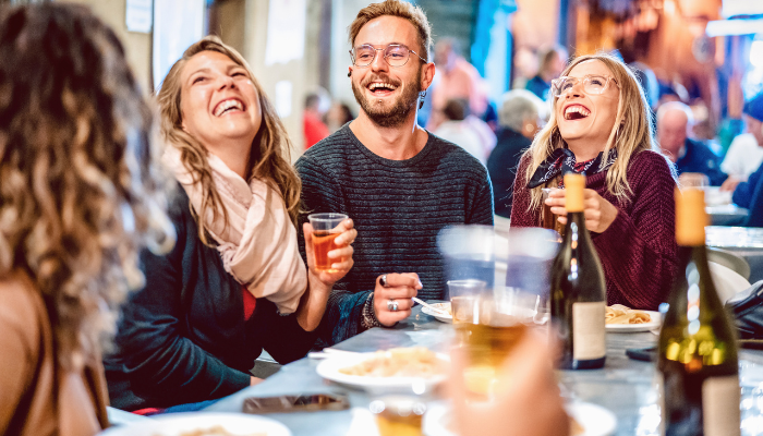 Group of people laughing and enjoying drinks and food together
