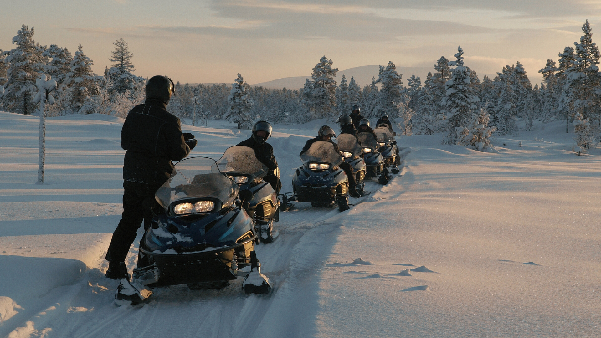 Group snowmobiling in the snow on a trail in the Black Hills, SD