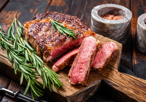 Delicious filet of steak on wood cutting board with rosemary