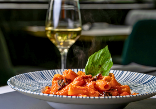 Plated red pasta with white glass of wine at restaurant 