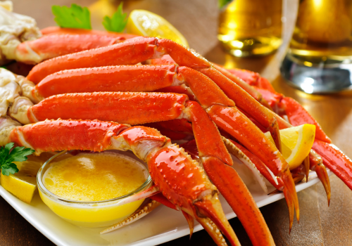 Bright red crab legs sitting on plate with butter and beers in the background