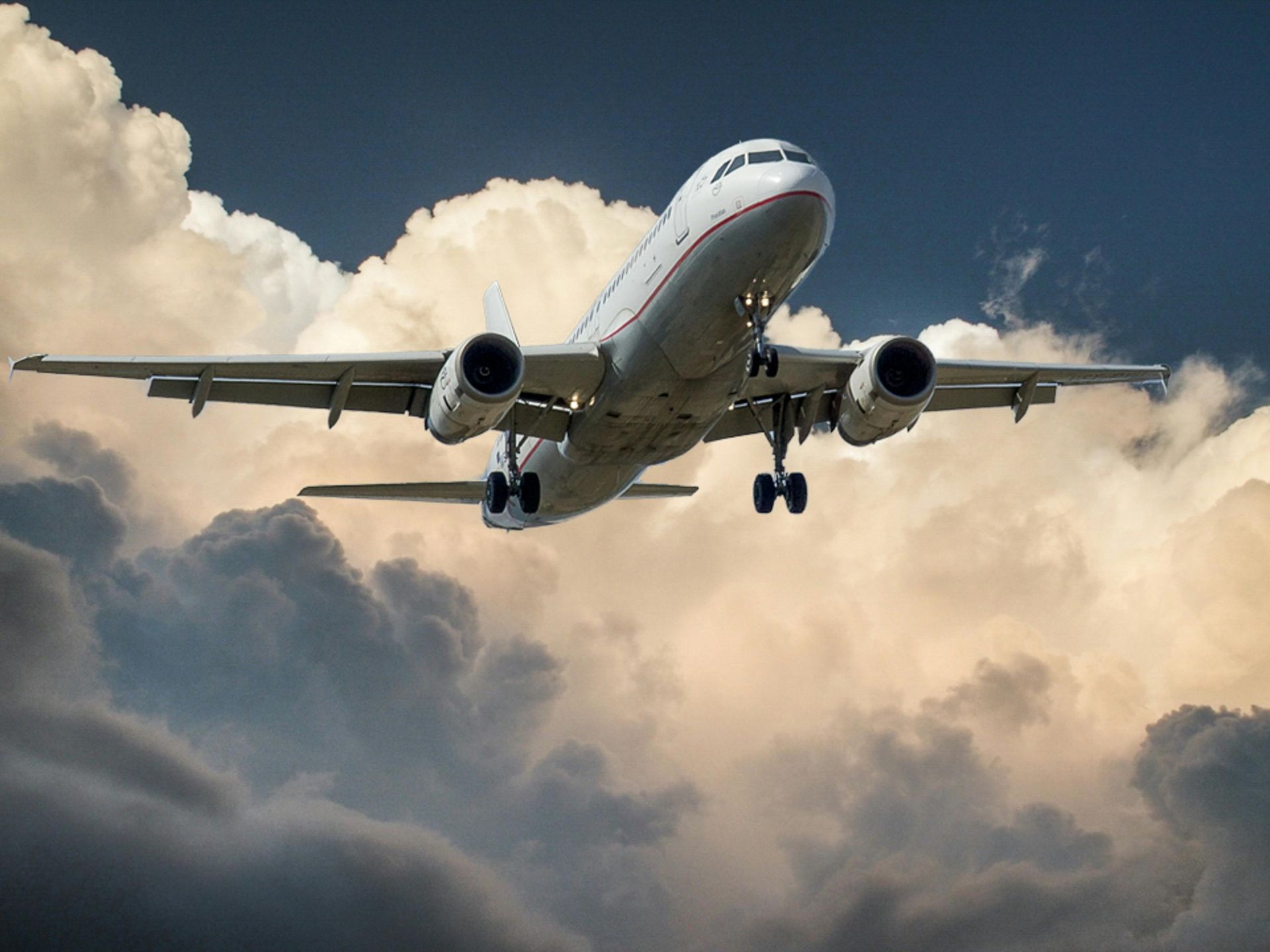 Plane traveling across open skies with golden clouds in the background