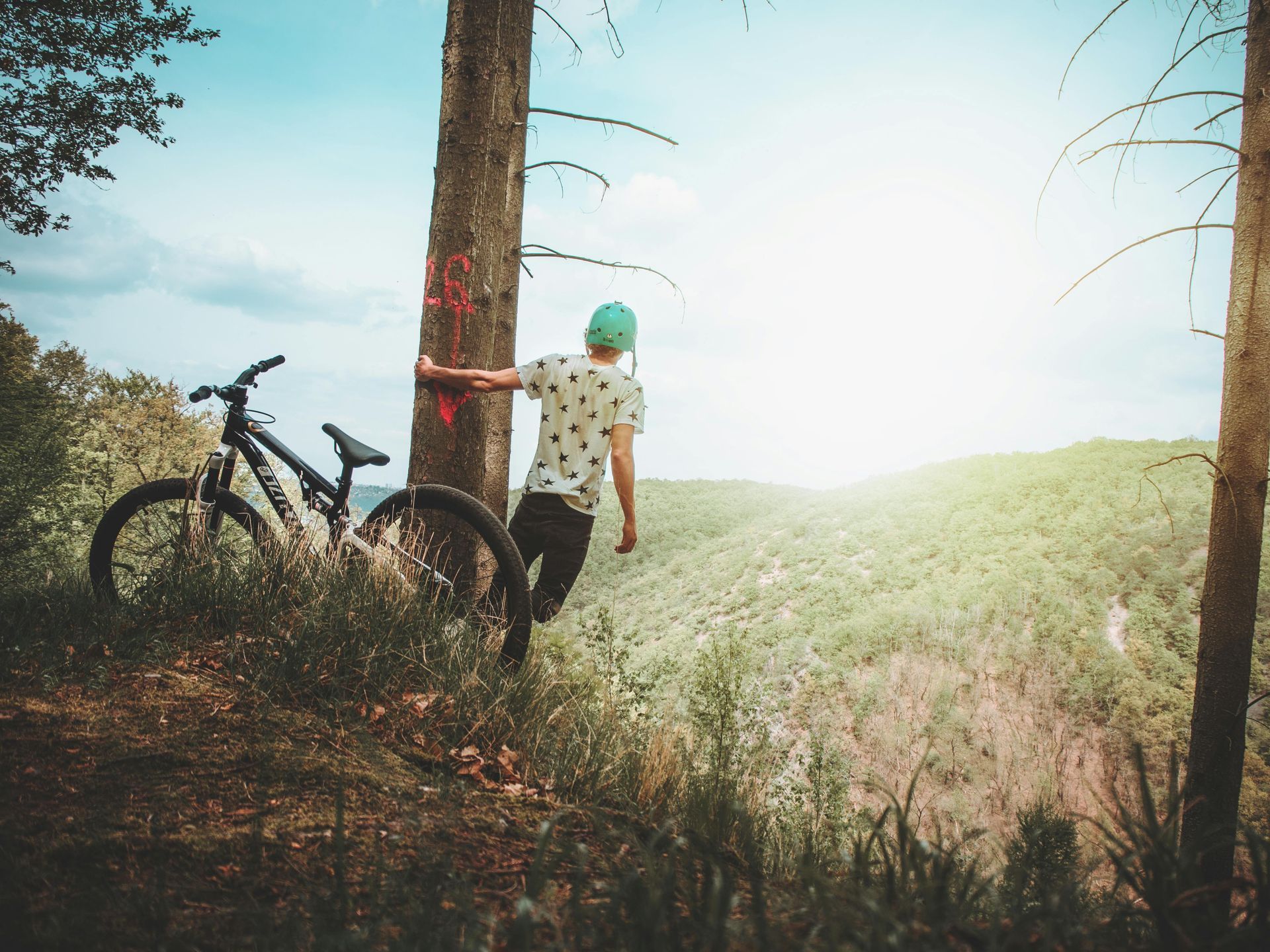 Person in the hills standing beside their bike overlooking the mountains