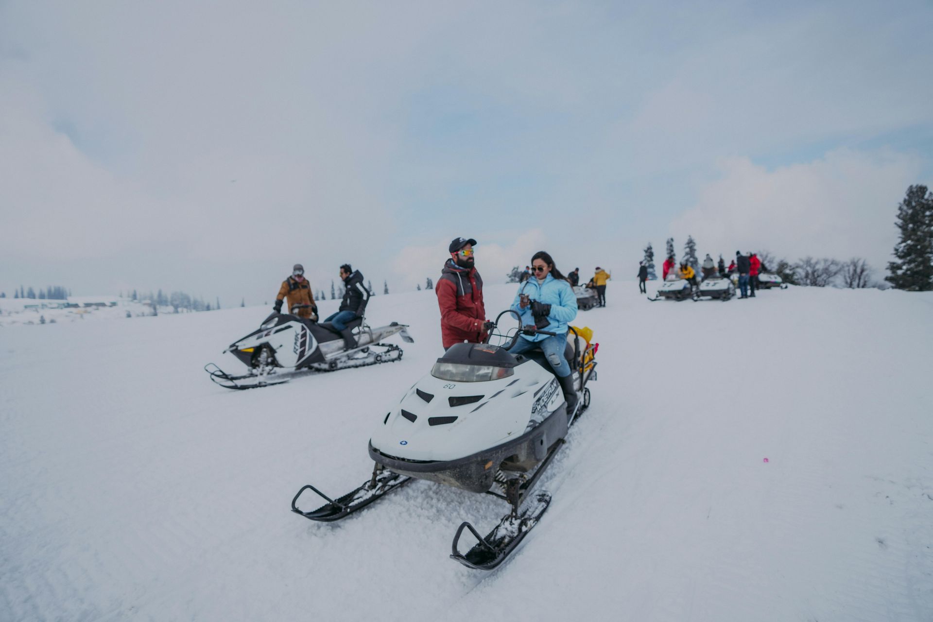 group of people sitting on snowmobiles in the snow