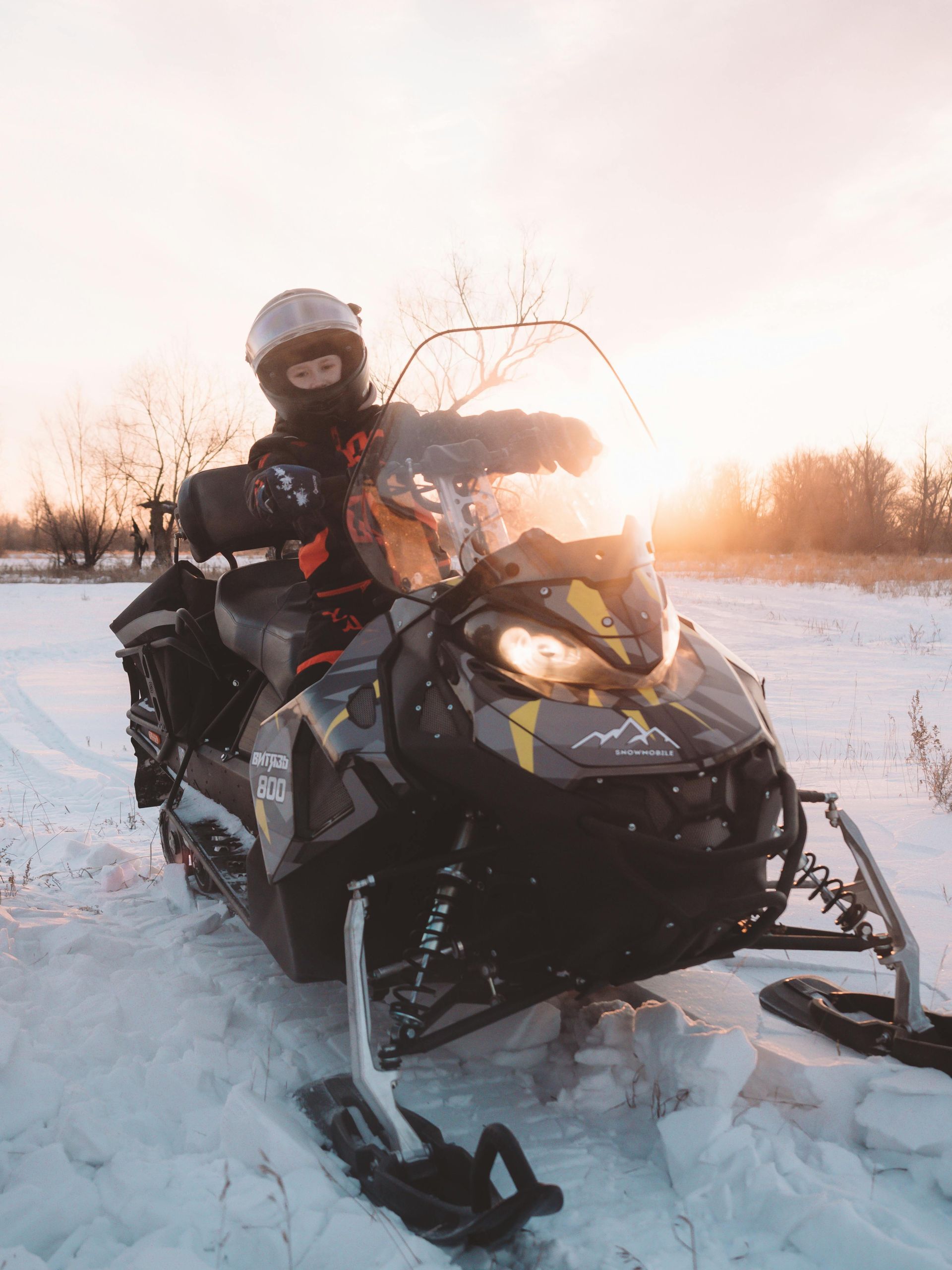 Person snowmobiling remote trails at sunset