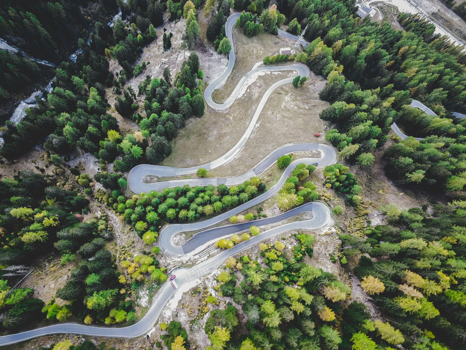 Aerial view with very curvy road with lush green pine trees surrounding road