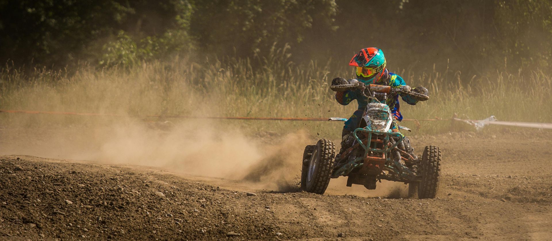Person riding ATV in a field, kicking up dirt behind him in the Black Hills