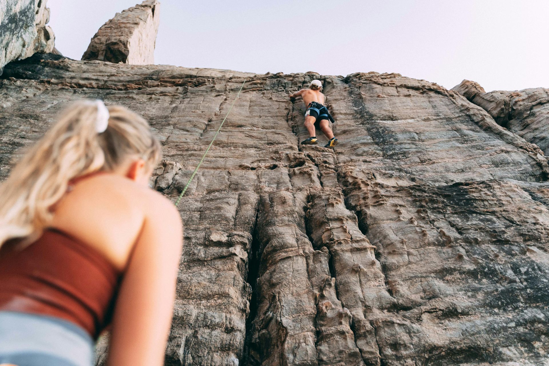 Two people outdoors with one person rock climbing